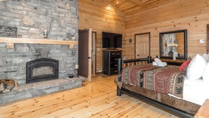A log cabin room with a stone fireplace, wooden ceiling, and a bed with a patterned blanket. - 
Kawagama Shoreline - Private Waterfront Cottage on Kawagama Lake (Dorset)