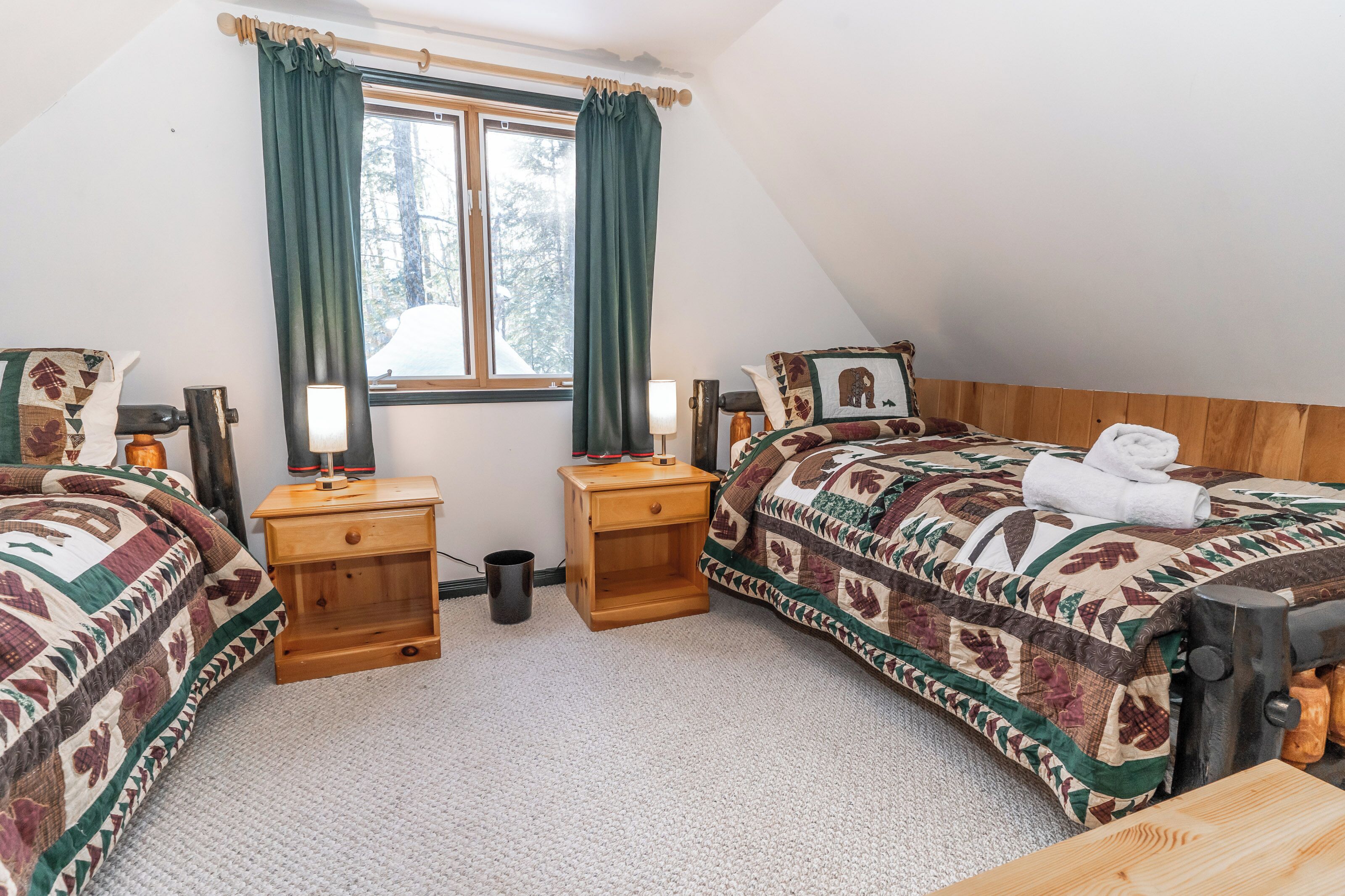 Un dormitorio acogedor con dos camas, una ventana con cortinas, una mesita de noche de madera y una lámpara.