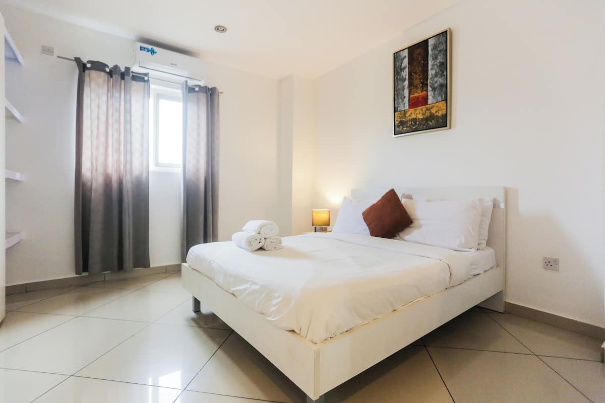 A hotel room with a bed, a bathroom, and a window with curtains.