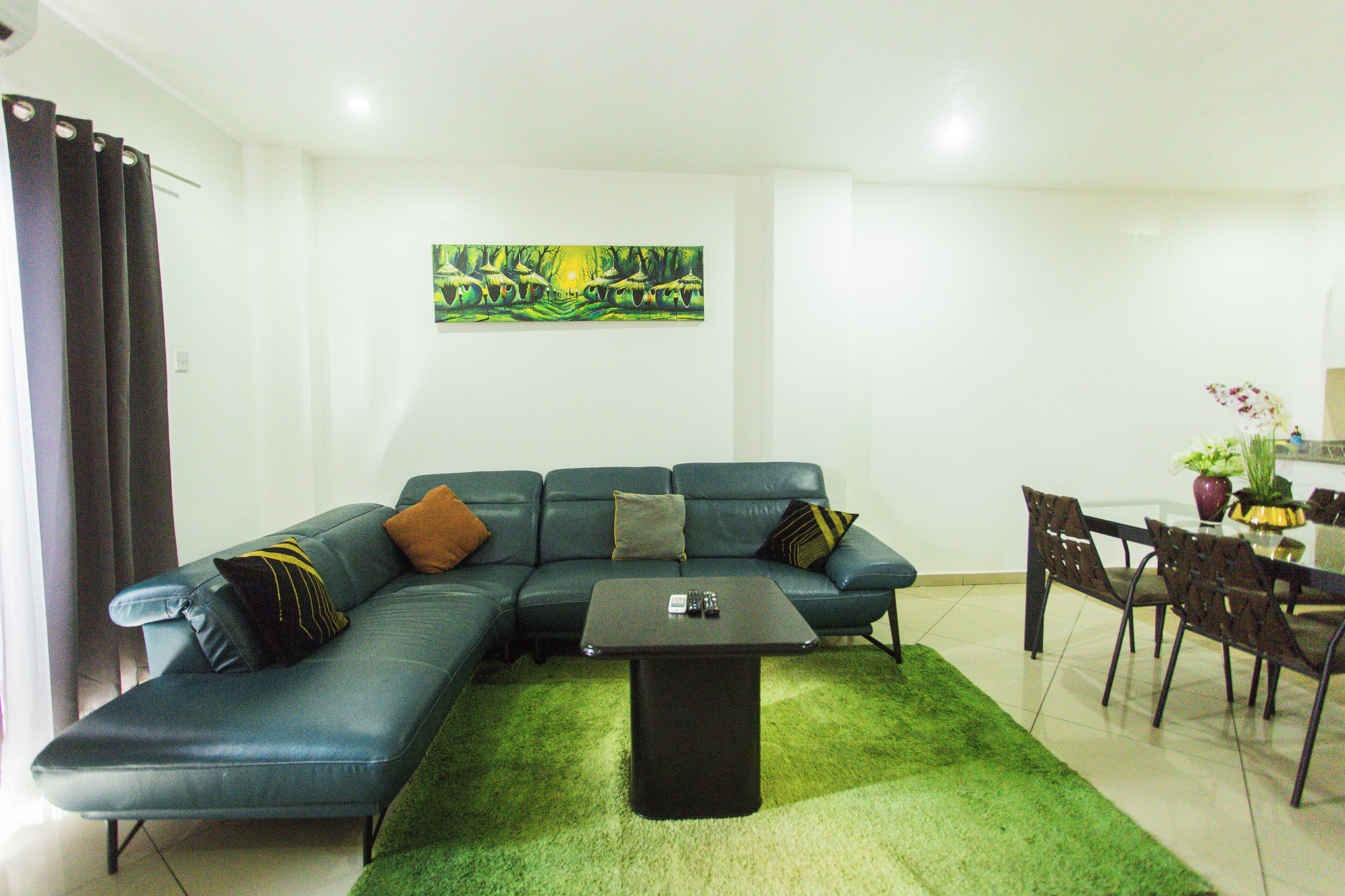 A living room with a sectional sofa, a coffee table, and a dining area with chairs and a table.