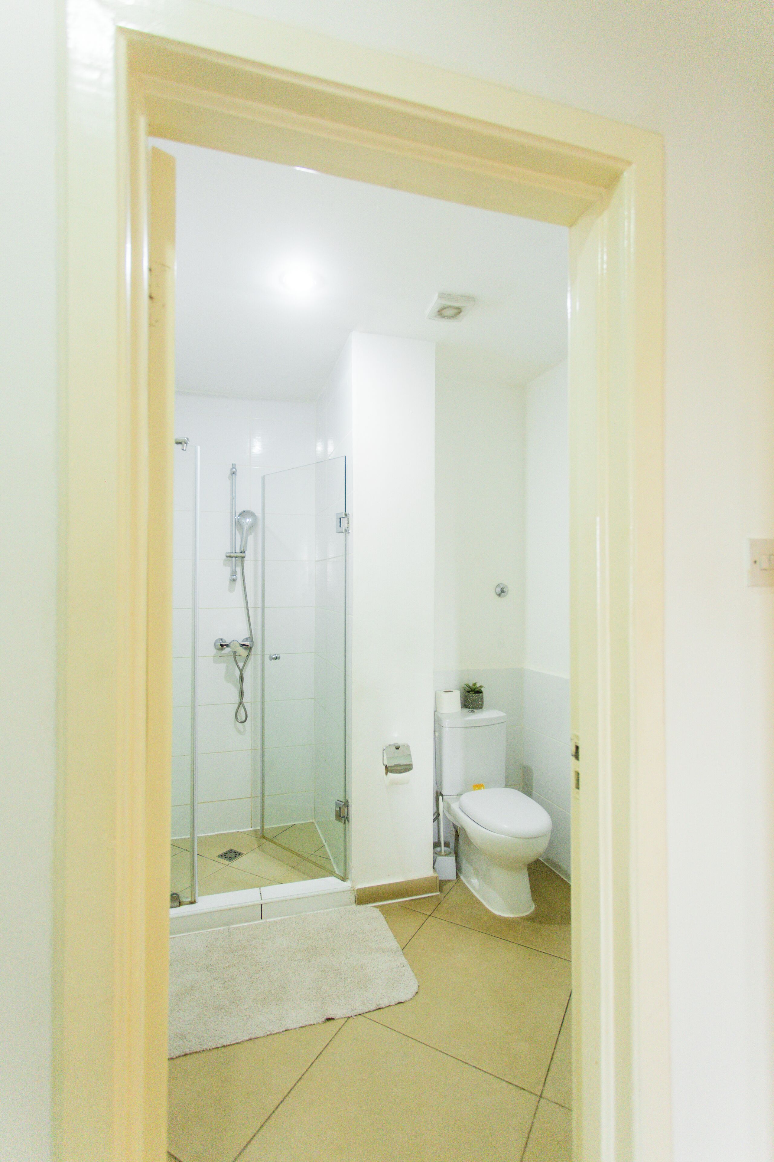 A bathroom with a glass shower enclosure, a toilet, and a white sink.