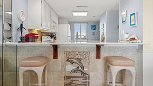 A kitchen with white cabinets, a tiled backsplash, and a central island with stools.