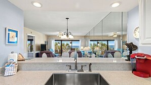 A modern kitchen with a large island, stainless steel sink, and a red coffee machine.