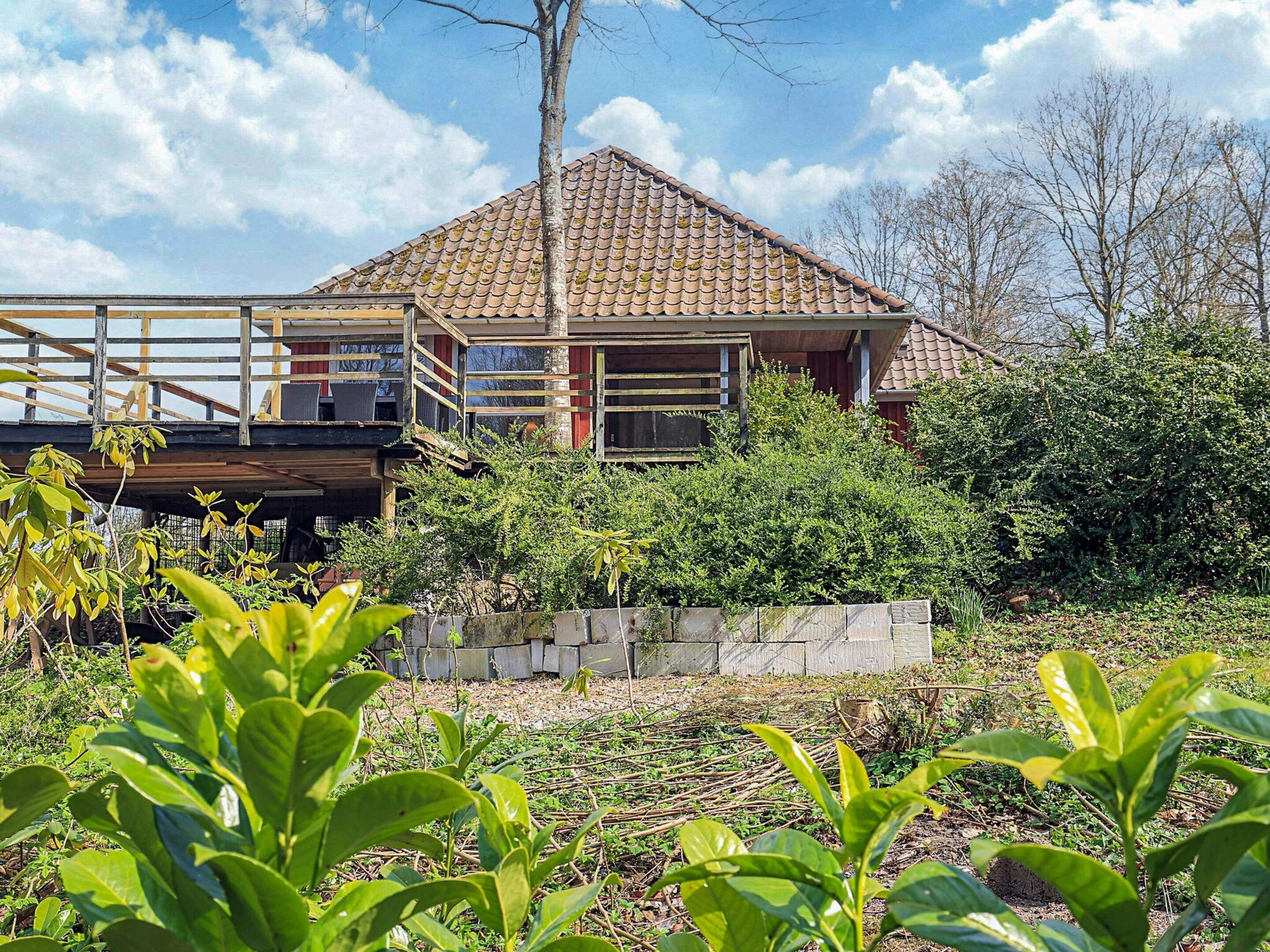 A two-story house with a tiled roof, a balcony, and a garden area.