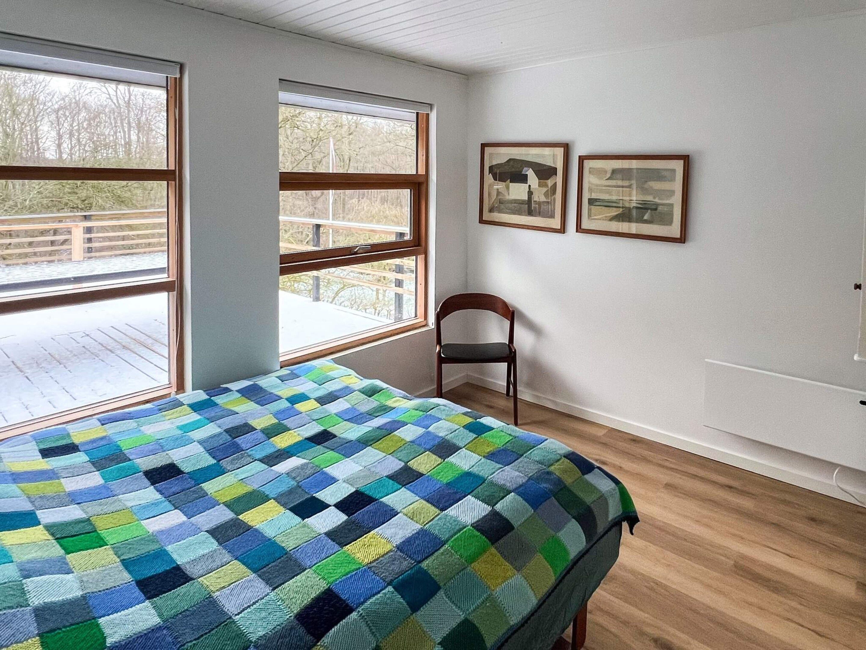 Ein Zimmer mit einem Bett, einem Sessel und zwei gerahmten Bildern an der Wand.