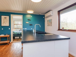 A modern kitchen with a dark countertop, a sink, and a window with a view of trees. - 6 Person Holiday Home in Asperup (Middelfart)