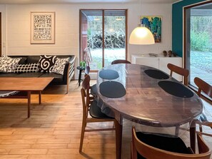 Zona pranzo moderna con tavolo rotondo, sedie e divano.