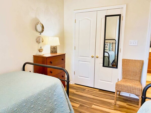Un dormitorio con cama, cómoda, silla y puerta con espejo.