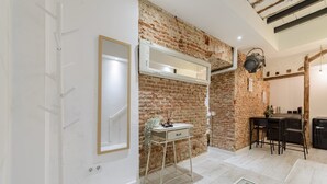 Une cuisine moderne avec un mur en briques, un plan de travail blanc et un coin repas avec des chaises.