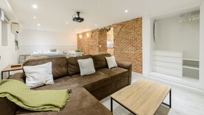 Un salon moderne avec un canapé marron, une table basse en bois et un mur en briques.