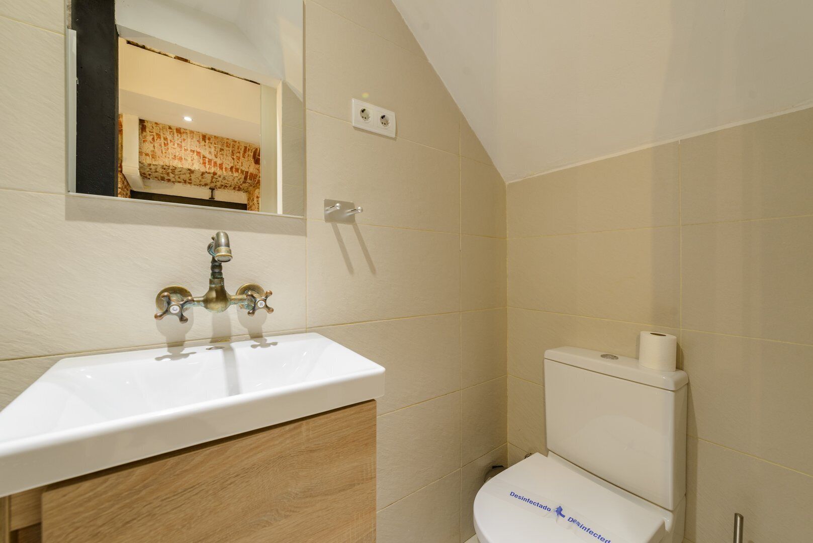Een badkamer met een wit wastafel, een spiegel en een toilet.