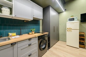Enjoy cooking in this well-equipped kitchen with a washing machine, microwave, and refrigerator.