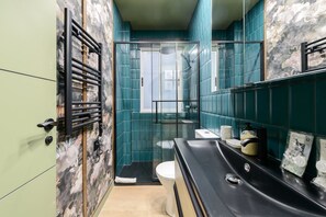 Efficient bathroom with a glass-enclosed shower, black sink, and white toilet.