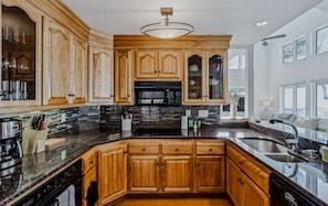 A kitchen with wooden cabinets, a central island, a microwave, and a large window.