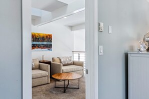 A modern living room with a sofa set, a coffee table, and a painting on the wall.