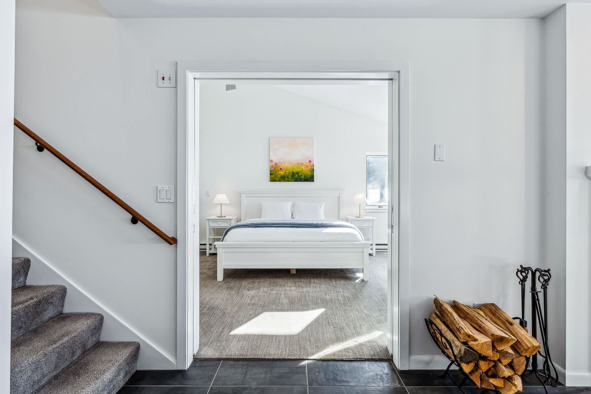 A modern bedroom with a bed, bedside tables, and a painting.