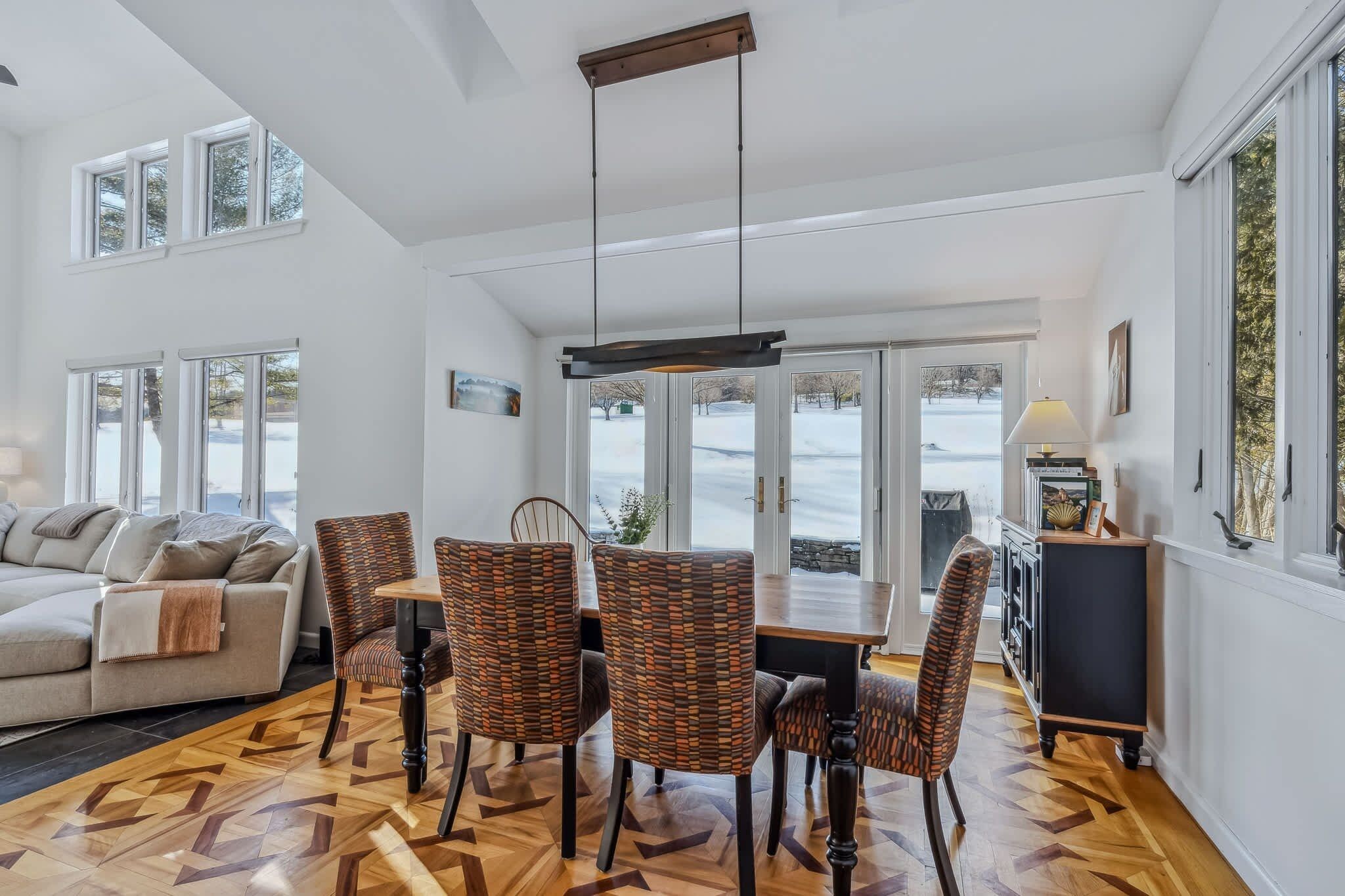 A spacious living area with a dining table, multiple chairs, a sofa, and a fireplace.