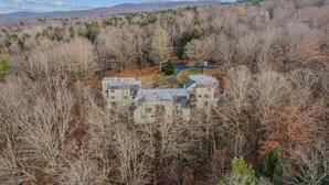 A multi-story building surrounded by dense forest, with a clear view of the surrounding landscape. - Condo near Ski Hill with Club Access, Kingswood (Quechee)