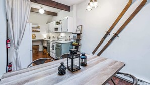 A kitchen with white cabinets, a microwave, and a stove. There is a dining table with two vases and a lantern. - Condo near Ski Hill with Club Access, Kingswood (Quechee)