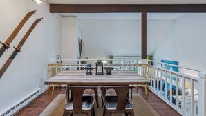 A dining area with a wooden table, metal chairs, and a railing overlooking a balcony. - Condo near Ski Hill with Club Access, Kingswood (Quechee)