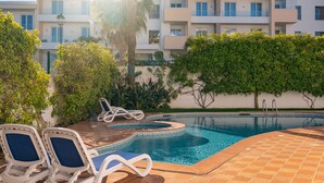 A swimming pool with two lounge chairs, surrounded by greenery and a tiled deck. - Lagos Ocean View 2 With Pool by Homing (Lagos)