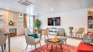 Een moderne woonkamer met een open haard, comfortabele zitplaatsen, een flatscreen televisie en een boekenkast.