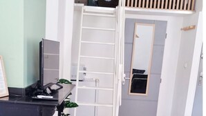 A room with a bunk bed, a desk with a computer, a round table with a mug and a candle, and a green blanket on a couch. - Cosy mezzanine studio in Narbonne town center, close to beaches (Narbonne)