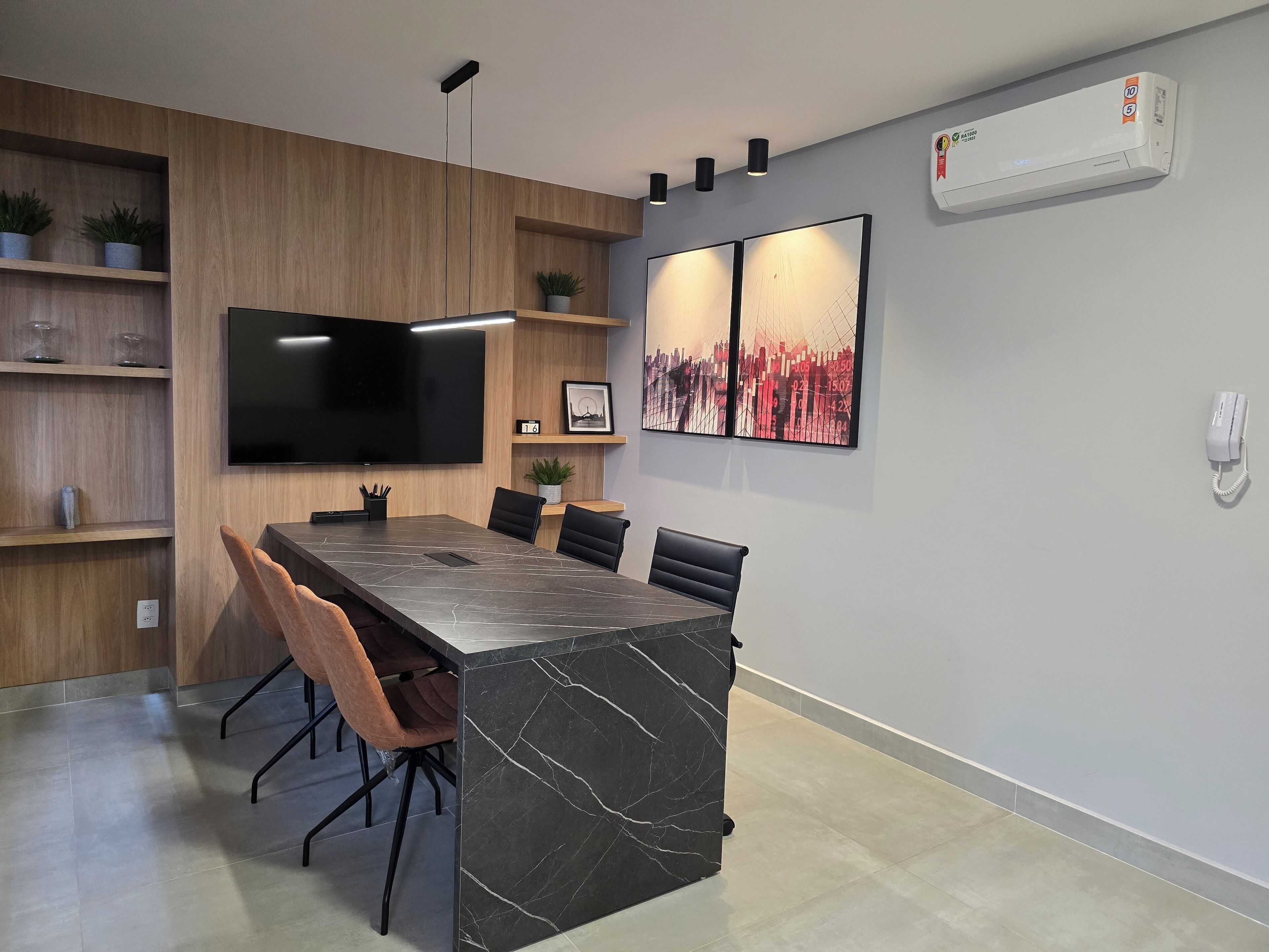 A modern dining area with a marble island, black chairs, and a flat-screen TV mounted on the wall.