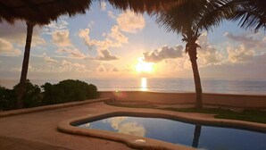 Una piscina amb vista al capvespre, envoltada de palmeres i un cel serè.