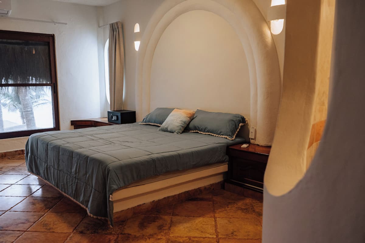 Ein Schlafzimmer mit einem Bett, Nachttischen, einem Fenster und einer gewölbten Wand.