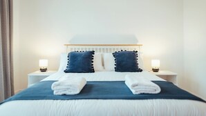 Un lit bien fait, avec deux oreillers, deux lampes de chevet et une serviette pliée posée sur le lit.