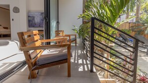 Un salon moderne avec un banc en bois, un téléviseur et un escalier menant à un espace extérieur agrémenté de plantes.