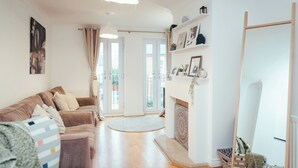 A spacious living room with a large sofa, a fireplace, and a view through the glass doors. - Contractors Retreat- Free Parking (Chelmsford)