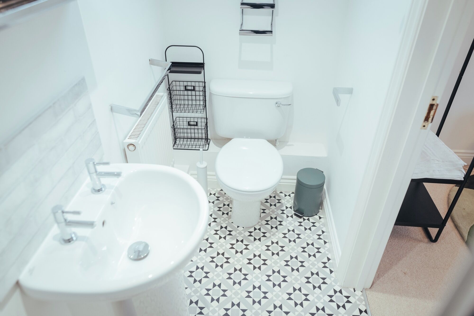 A small bathroom with a white sink, toilet, and shower.