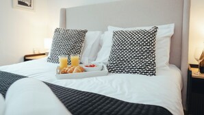 A neatly made bed with a tray of croissants, orange juice, and a bowl of strawberries. - Contractors Retreat- Free Parking (Chelmsford)