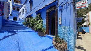 A building with a blue exterior, a sign for 'Hostel Aline', and a staircase leading to the entrance. - aline hostel (Chefchaouen)
