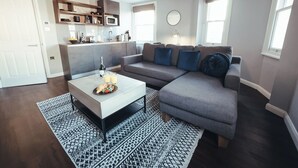 A modern living room with a grey sectional sofa, a white coffee table, and a patterned rug. - London Luxury Apartment on Rupert Street (London)