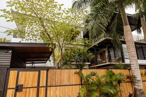 Ein modernes Gebäude mit Holzzaun, Balkon und tropischen Pflanzen.