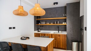 Una cucina moderna con mobili in legno, un piano di lavoro bianco e due lampade a cestino appese.