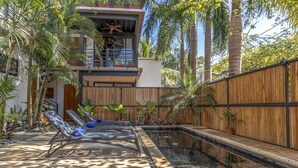 Ein modernes Haus mit Pool, Liegestühlen und tropischen Pflanzen.