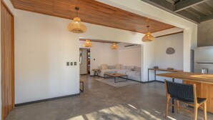 Un vaste espace de vie doté d’un plafond en bois, d’un canapé, d’une table basse et d’une table à manger avec des chaises.