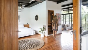 Un dormitorio moderno con una cama grande, un ventilador de techo, una planta en maceta y vistas al exterior.