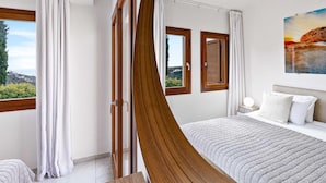 Une chambre à coucher avec un lit, une table de chevet, une fenêtre avec des rideaux et une vue sur l’extérieur.