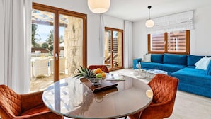 Un salon moderne avec une table à manger en verre, un canapé bleu et un balcon offrant une vue dégagée.