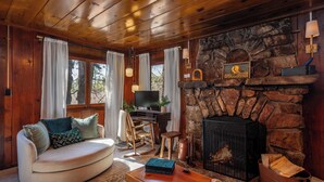 A cozy living room with a stone fireplace, wooden ceiling, and a comfortable sofa.