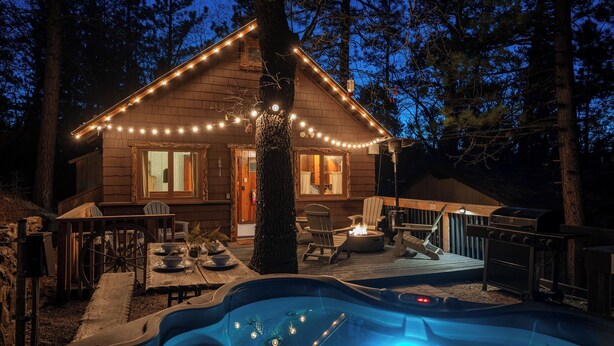 A cabin with a hot tub, deck, and string lights.