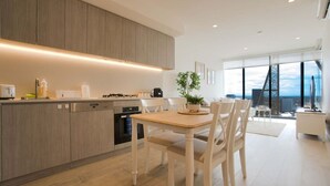 A modern kitchen with a dining area, large windows, and a view of the city. - Luxury Apt in Rundle Mall with Beautiful City View (Adelaide)