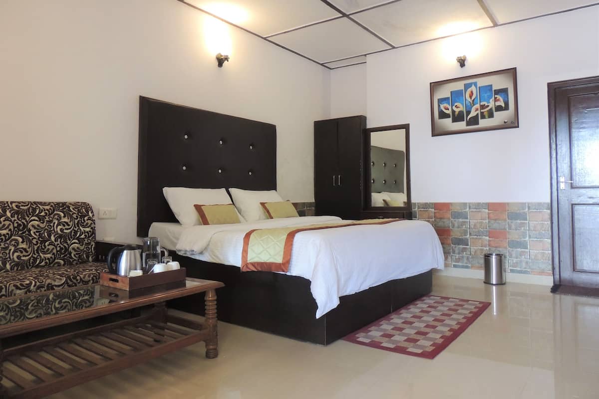 A hotel room with a bed, a sofa, a coffee table, a wardrobe, and a bathroom.