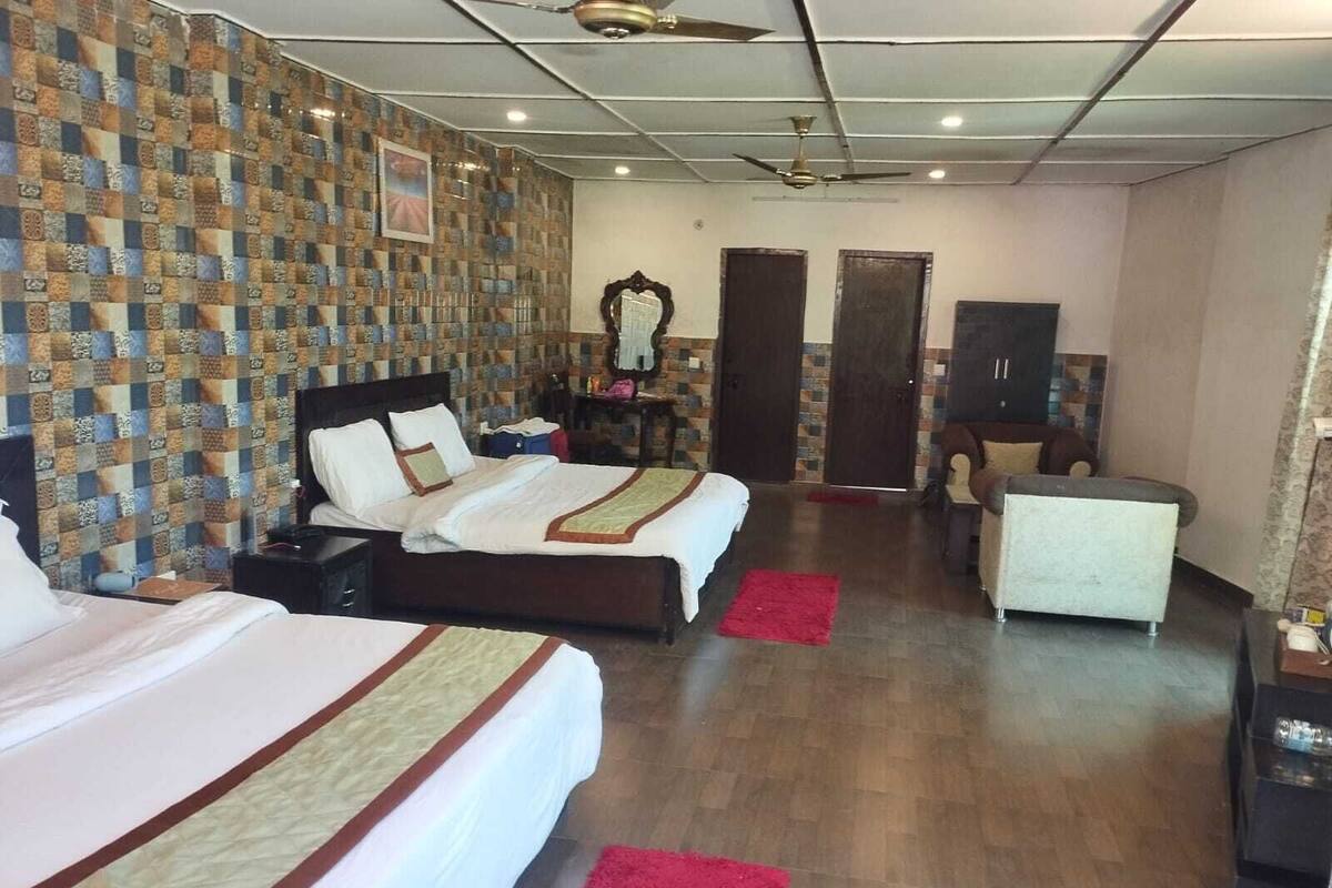 A hotel room with two beds, a desk, a chair, a wardrobe, and a mirror.