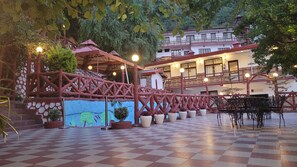 A checkered courtyard with a covered seating area and a building in the background. - Ceyone Classic Fall Resort (Mussoorie)